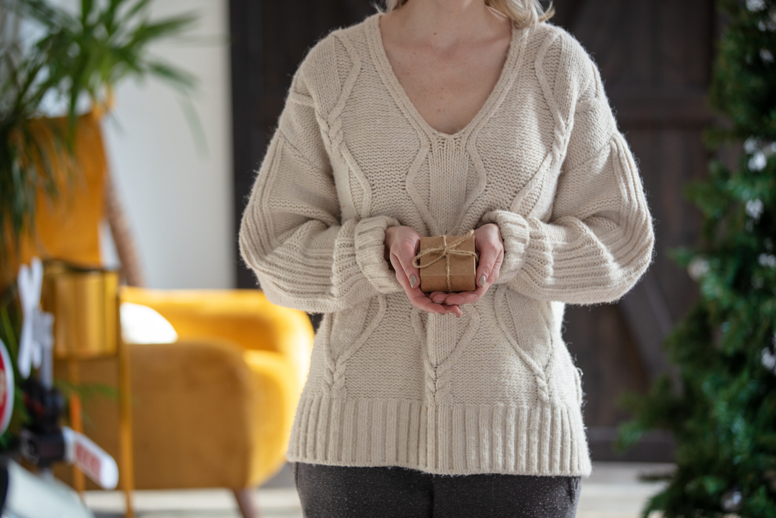 Woman in sweater holds gift box at home